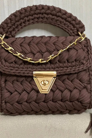 Brown woven handbag with gold chain and clasp on a light background