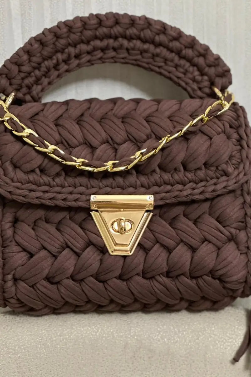 Brown woven handbag with gold chain and clasp on a light background