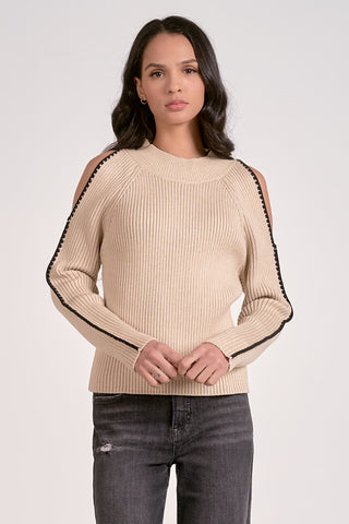 Woman wearing a beige sweater with black trim on a white background