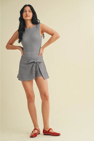 Woman wearing a checkered dress with red shoes on a beige background