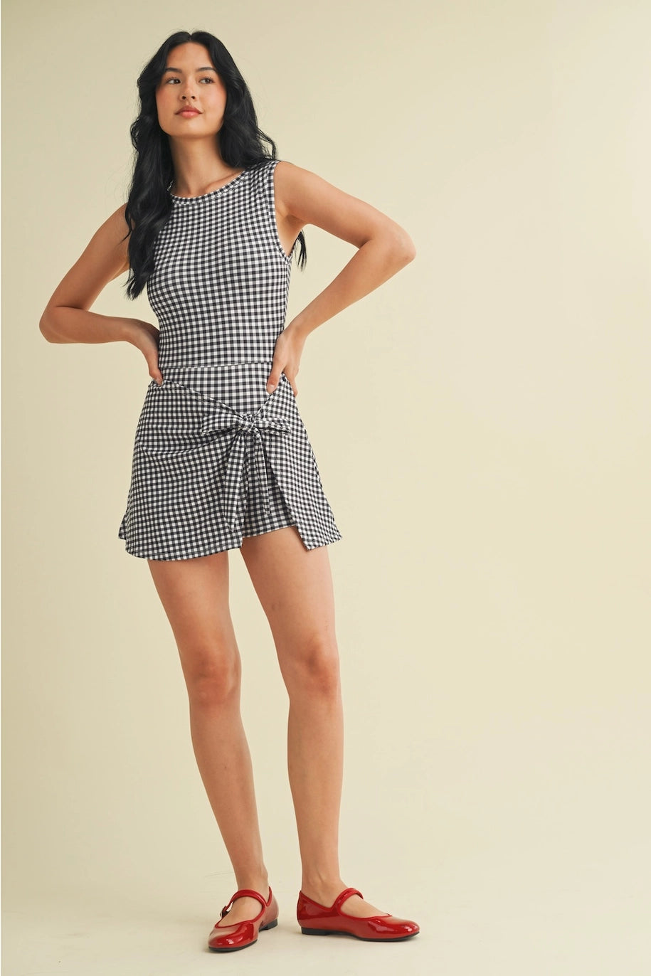 Woman wearing a checkered dress with red shoes on a beige background