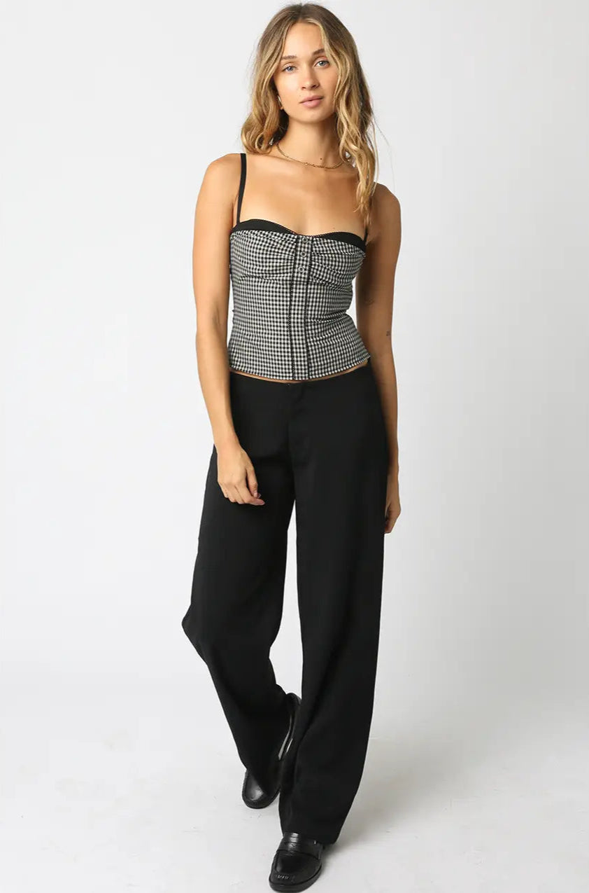 Woman wearing a black and white checkered top and black pants on a white background