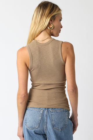 Person wearing a beige tank top and blue jeans on a white background