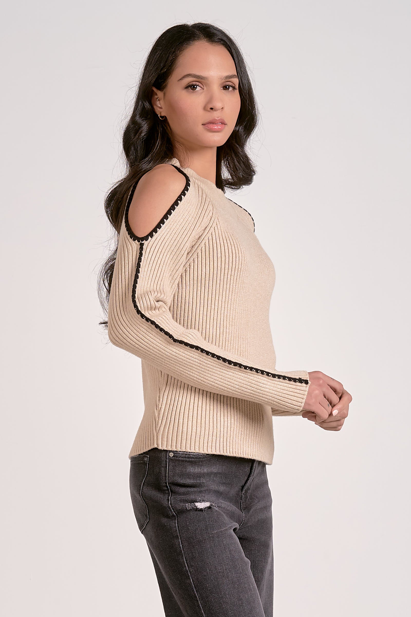 Woman wearing a beige sweater with black trim on a white background