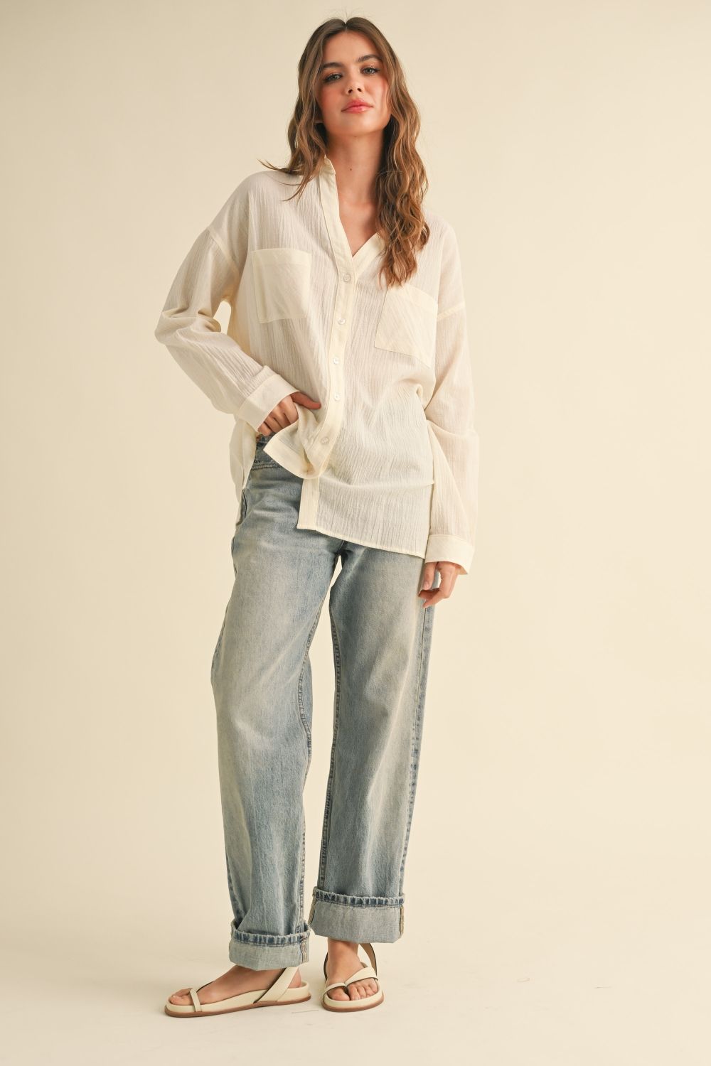 Woman wearing a white shirt and light blue jeans on a beige background