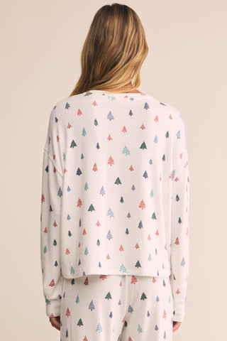 Person wearing a white long-sleeve shirt with colorful tree pattern on a beige background