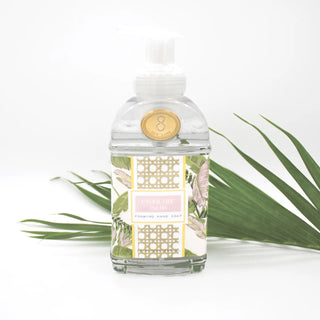 Clear bottle with decorative label and gold emblem on a white background with green leaves.