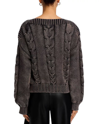 Person wearing a dark gray cable knit sweater on a white background