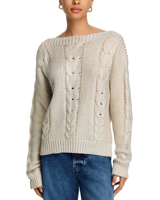 Woman wearing a beige cable knit sweater with blue jeans on a white background