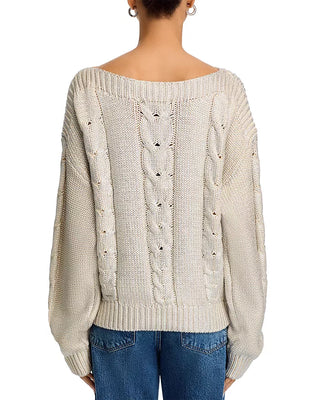 Beige cable knit sweater worn by a person on a white background