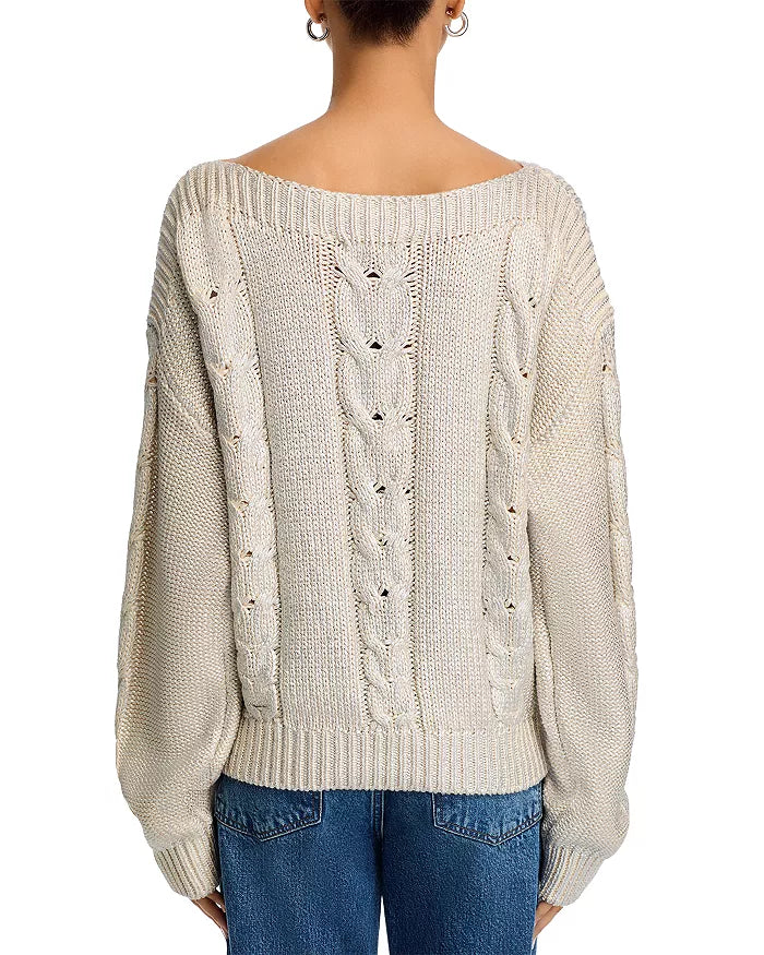 Beige cable knit sweater worn by a person on a white background