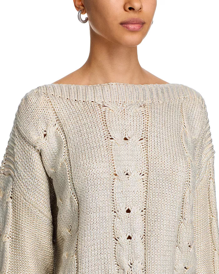 Close-up of a person wearing a beige knitted sweater with intricate patterns.