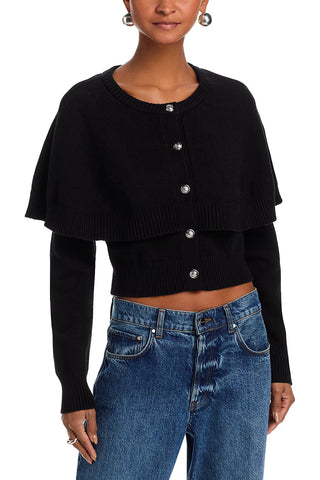 Person wearing a black cropped cardigan with silver buttons and blue jeans on a white background