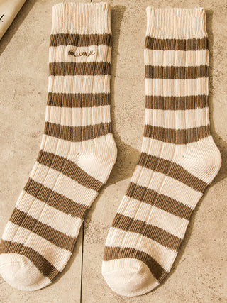 Pair of brown and white striped socks on a textured surface
