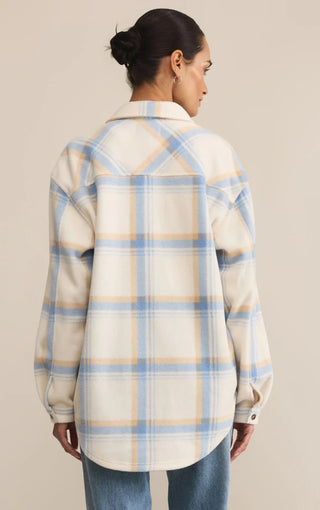 Woman wearing a plaid shirt with blue and beige pattern on a beige background