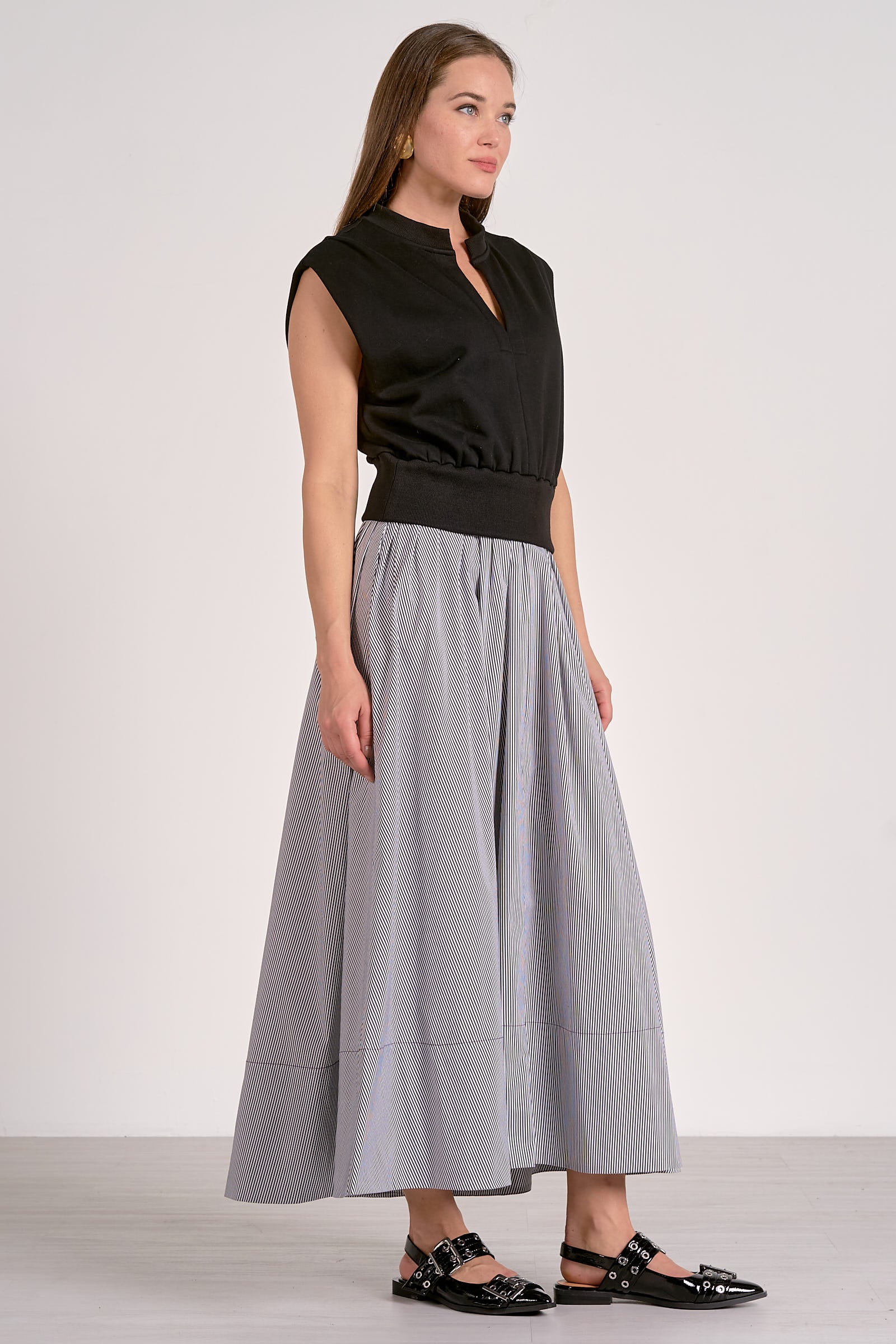 Woman wearing a black sleeveless top and gray wide-leg pants on a white background