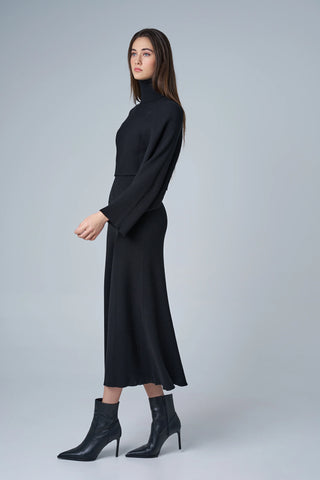 Woman wearing a black dress with long sleeves on a gray background