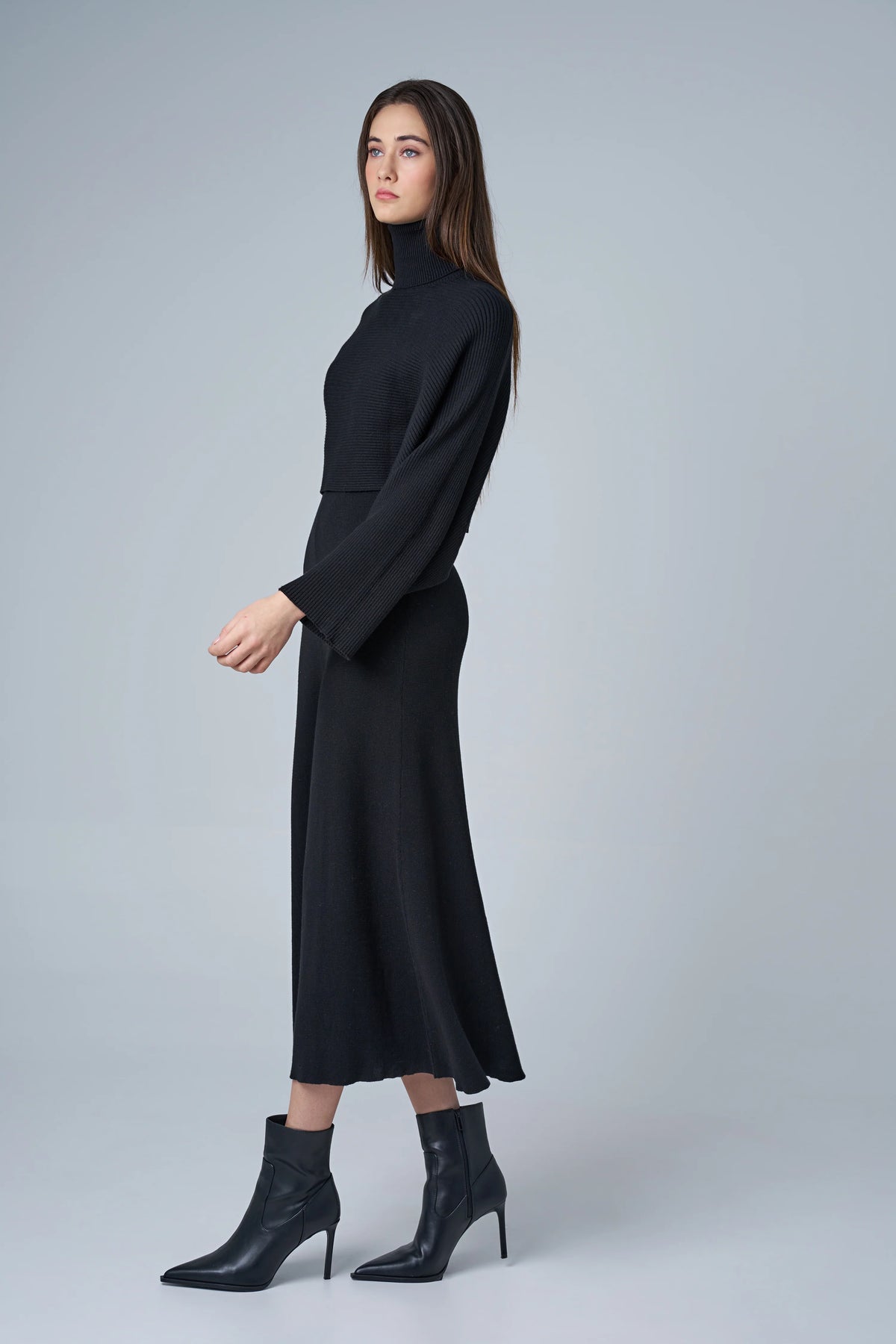 Woman wearing a black dress with long sleeves on a gray background