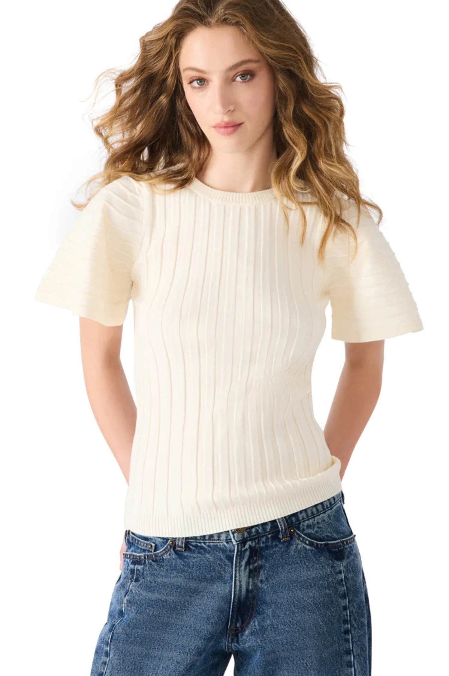 Woman wearing a white ribbed sweater and blue jeans on a white background