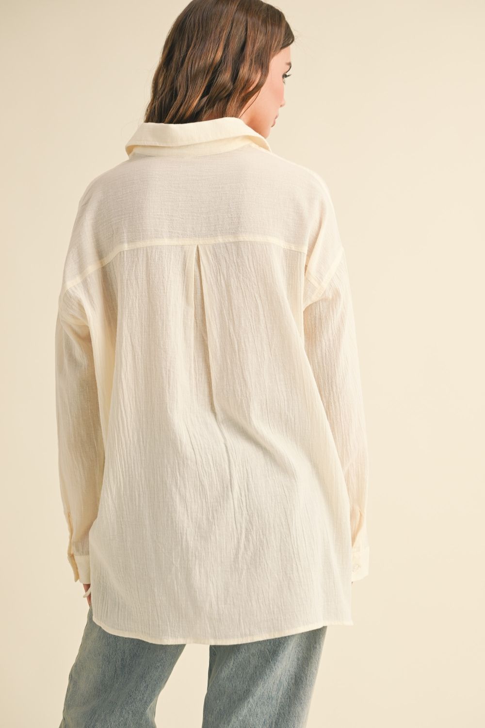 Person wearing a cream-colored shirt against a beige background