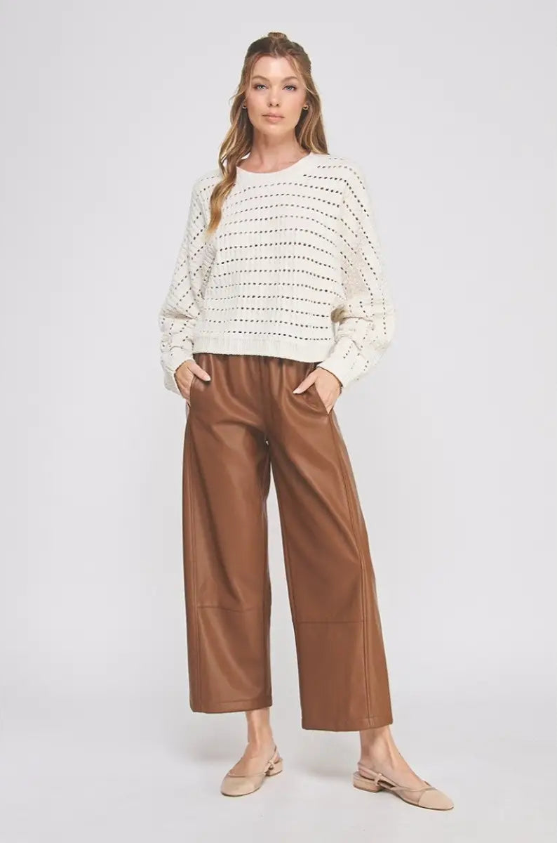 Woman wearing a white sweater and brown pants on a white background