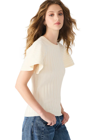 Woman wearing a cream ribbed sweater and blue jeans on a white background