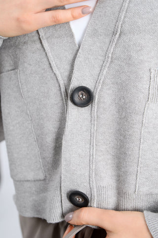 Close-up of a gray cardigan with buttons being adjusted.