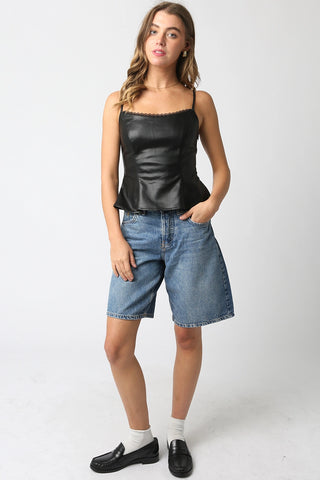 Woman wearing a black peplum top and blue denim shorts on a white background