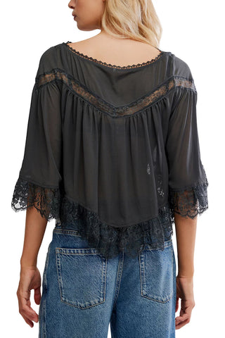 Black lace-trimmed blouse worn by a person on a white background