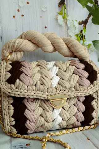 Woven handbag with braided handle on a light wooden surface