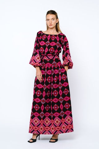 Woman wearing a long, patterned dress with a white background