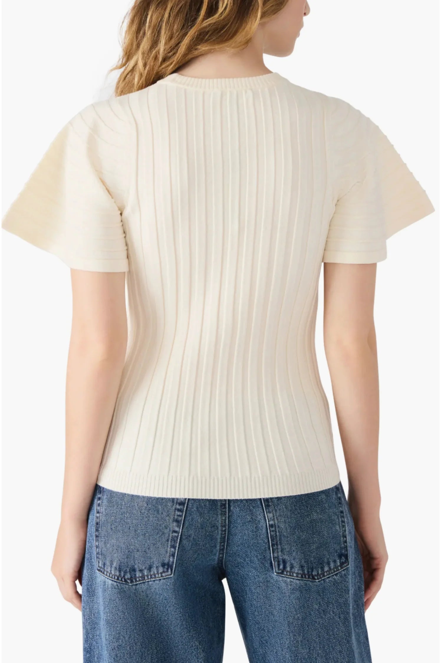 Person wearing a cream ribbed sweater and blue jeans on a white background