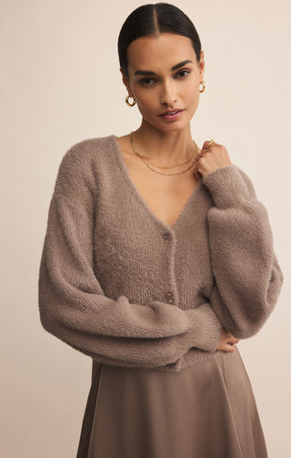 Woman wearing a brown cardigan against a beige background