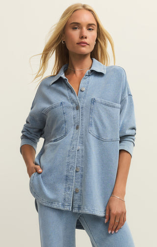 Woman wearing a light blue denim shirt against a plain background