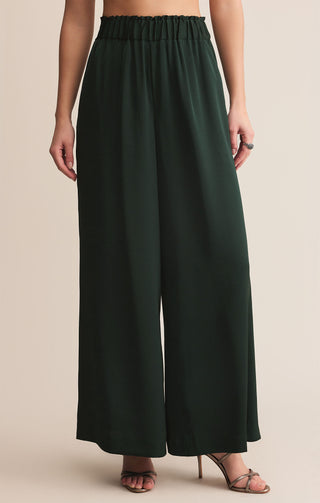 Dark green wide-leg pants worn by a person on a beige background