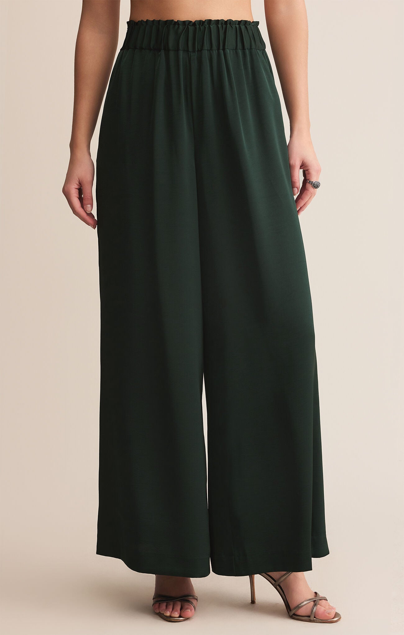 Dark green wide-leg pants worn by a person on a beige background