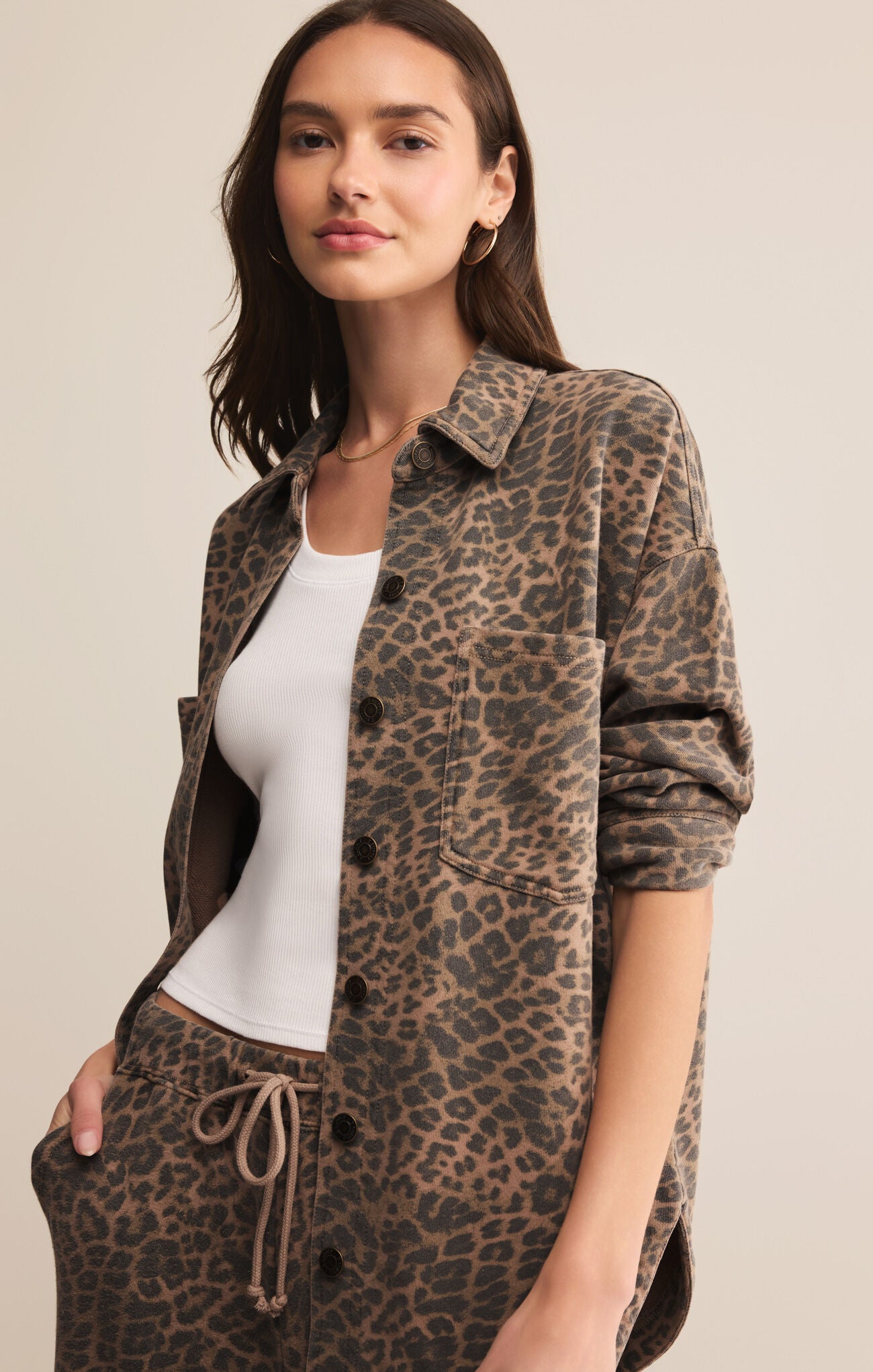 Woman wearing a leopard print shirt and pants on a beige background