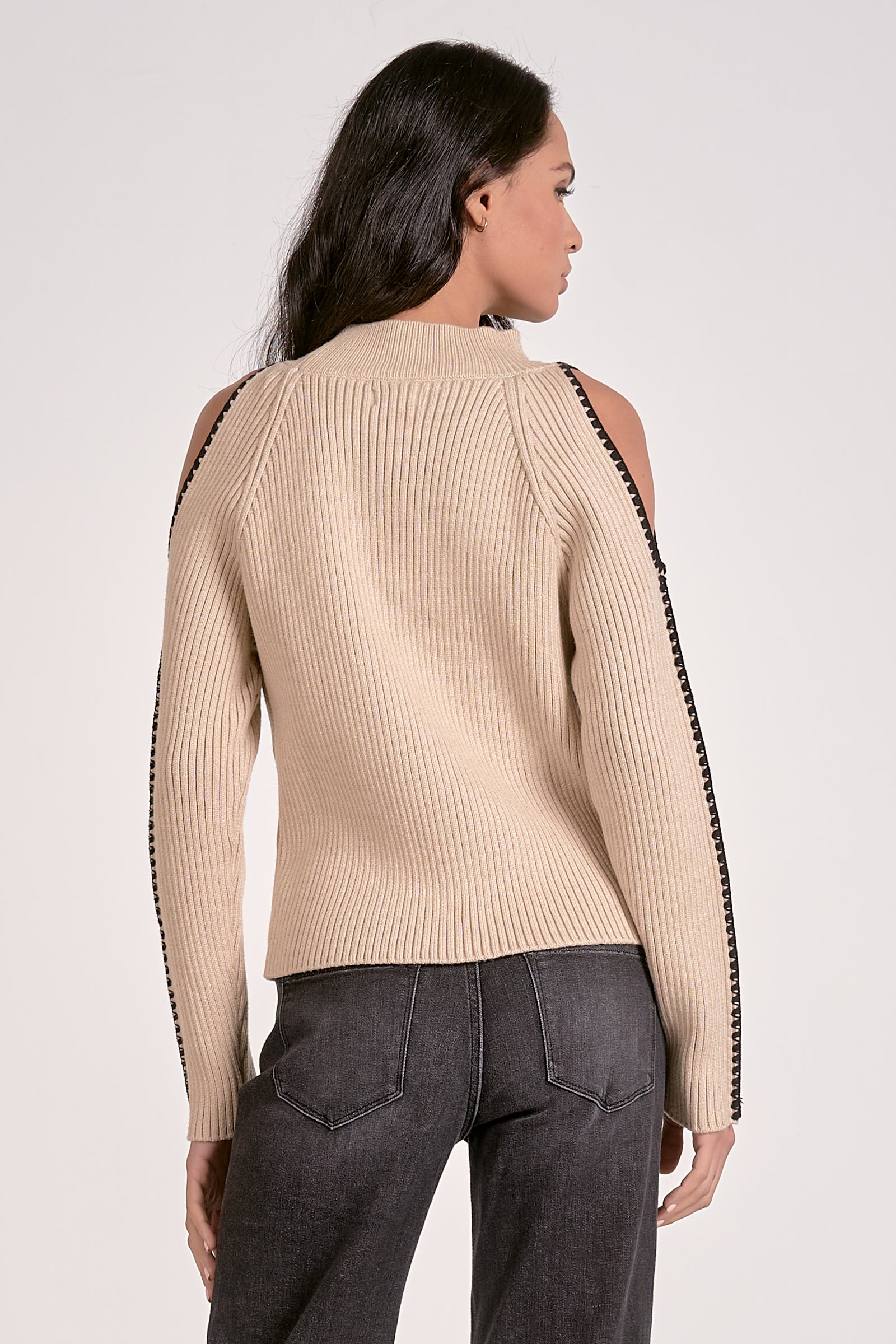 Woman wearing a beige sweater with black trim on a white background