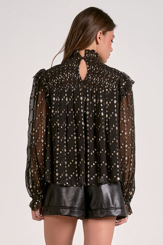 Woman wearing a black blouse with sheer sleeves and a cut-out back design on a white background