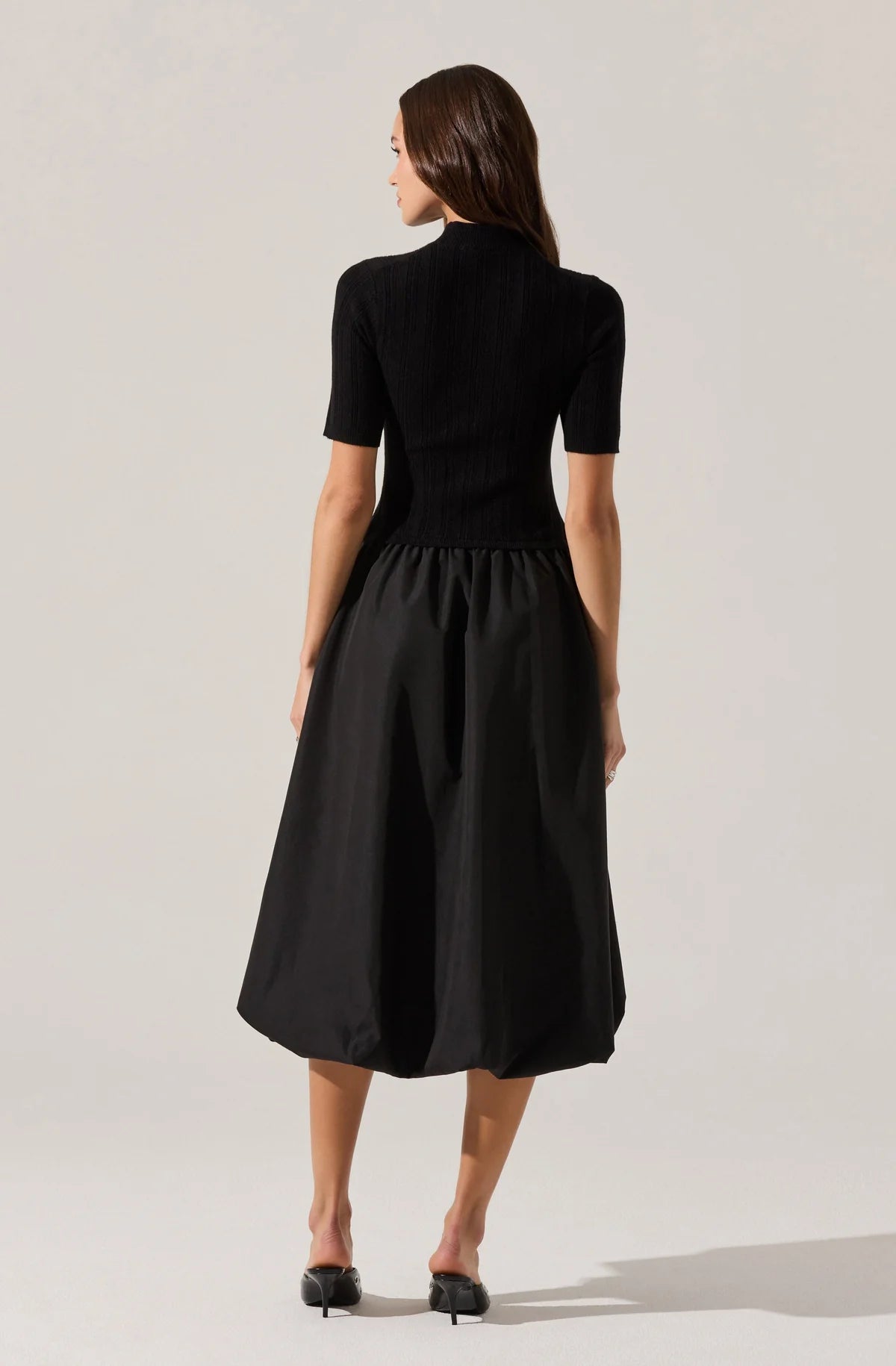 Woman wearing a black dress against a plain background