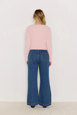 Person wearing a pink sweater and blue jeans on a white background