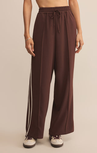 Brown wide-leg pants worn by a person on a beige background