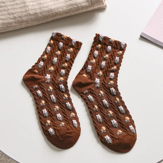 Pair of brown socks with teddy bear pattern on a light surface