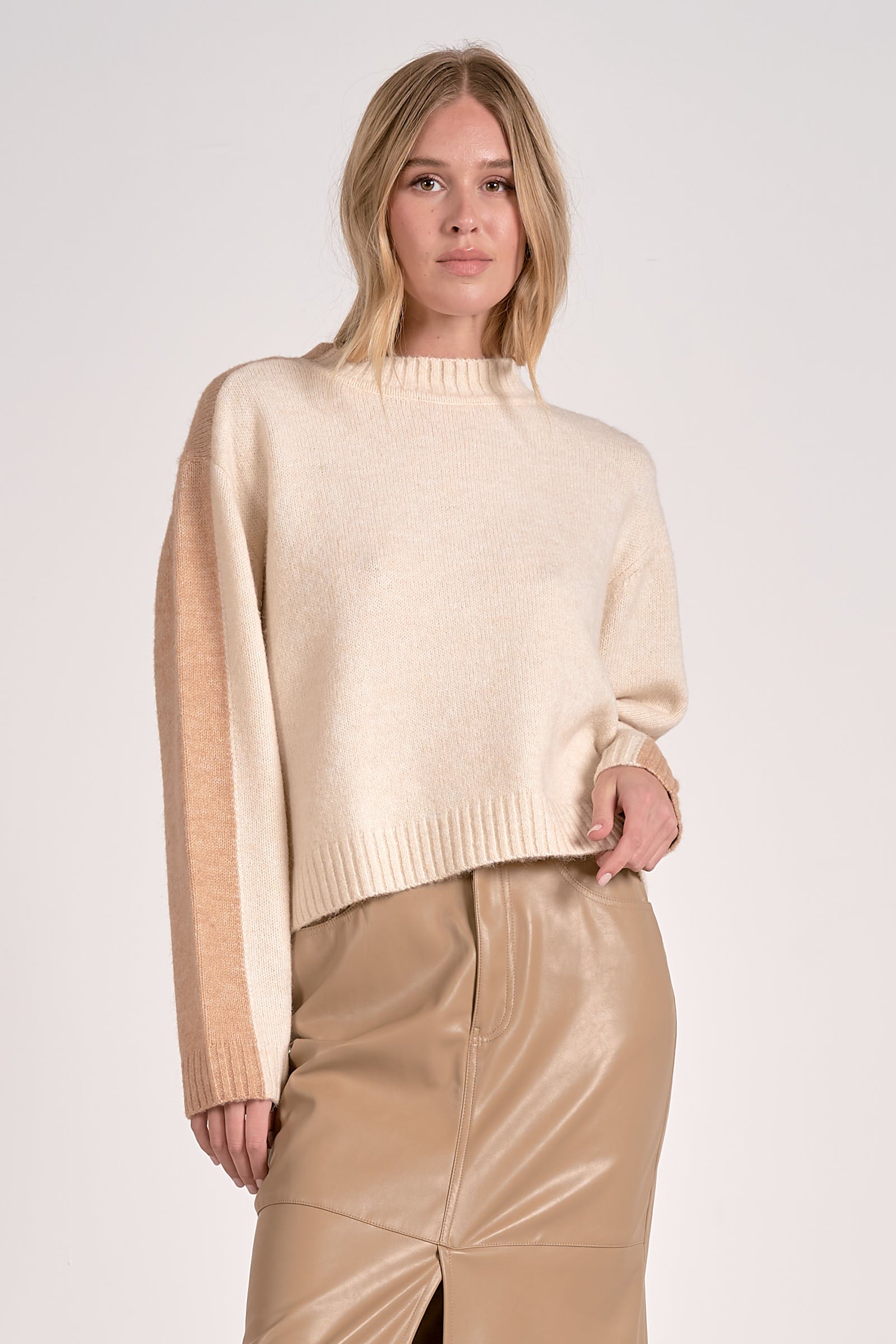 Woman wearing a beige sweater with a gradient effect and beige pants on a white background