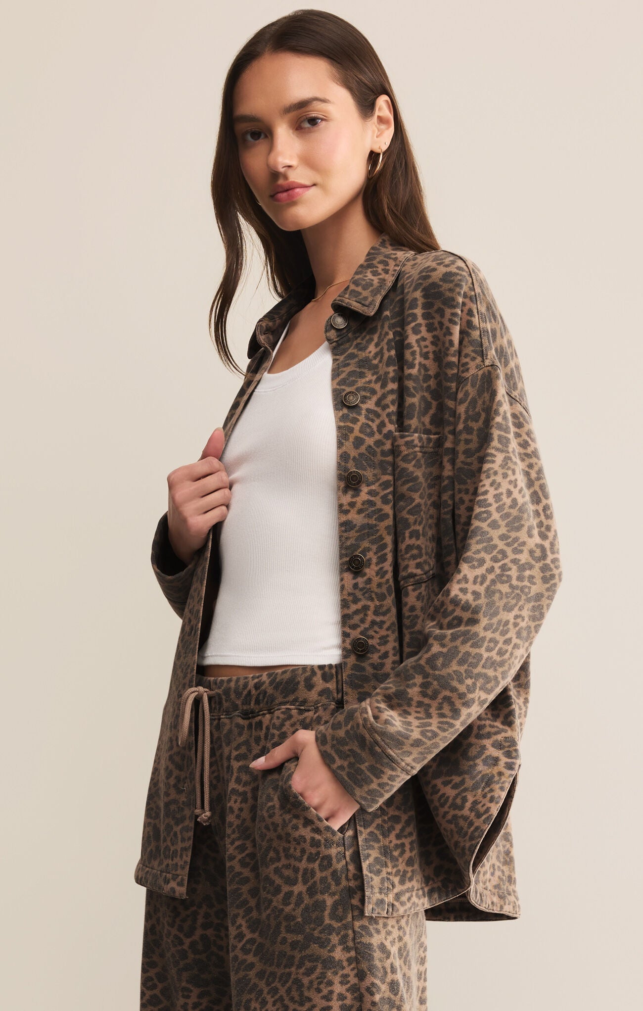 Woman wearing a leopard print jacket and pants on a beige background