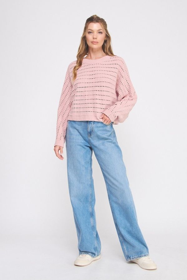 Woman wearing a pink patterned sweater and blue jeans on a white background