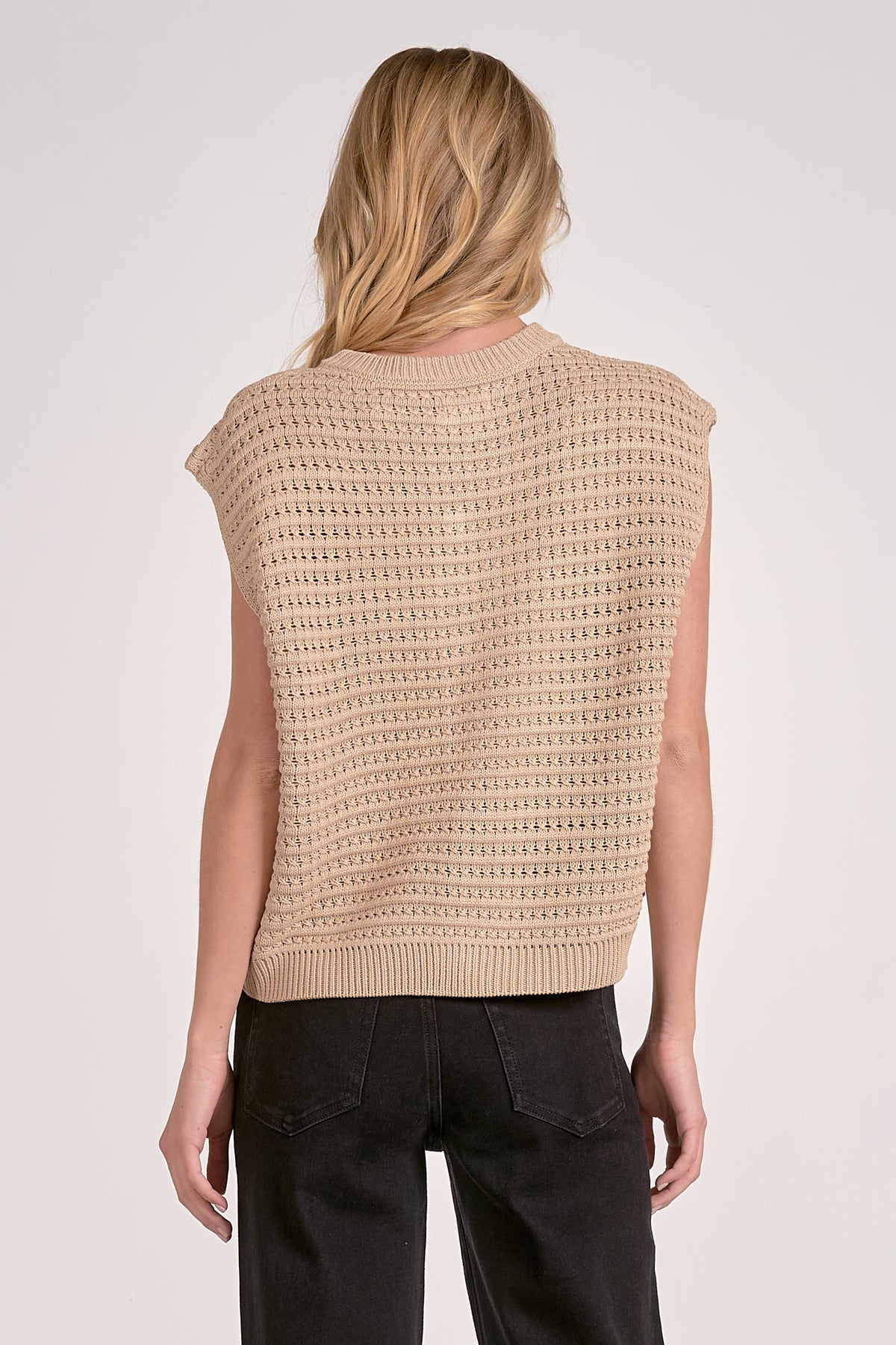 Beige knitted vest worn by a person on a white background