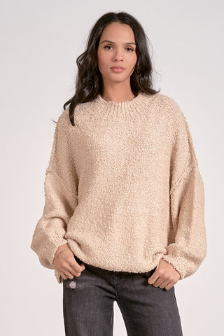 Woman wearing a beige sweater against a white background