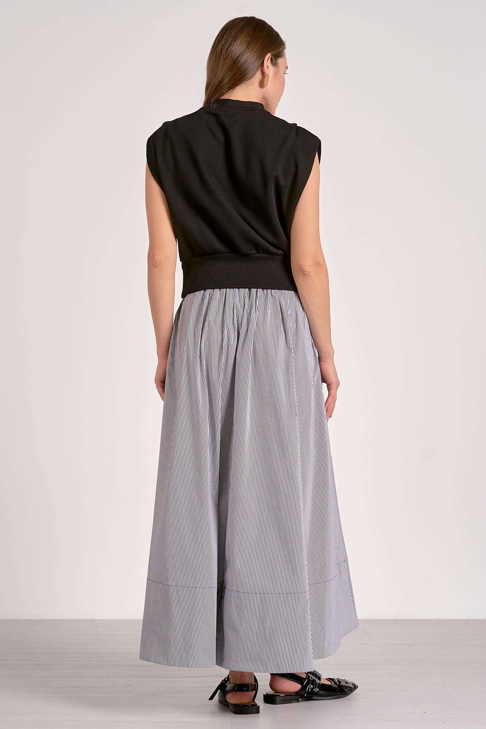 Woman wearing a black sleeveless top and gray skirt on a white background