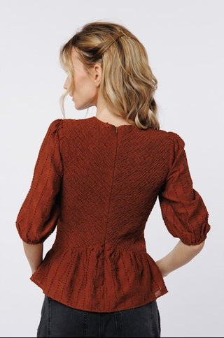 Woman wearing a rust-colored blouse with puffed sleeves on a white background